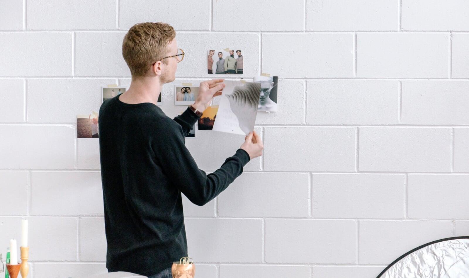 man mind mapping on white brick wall with images
